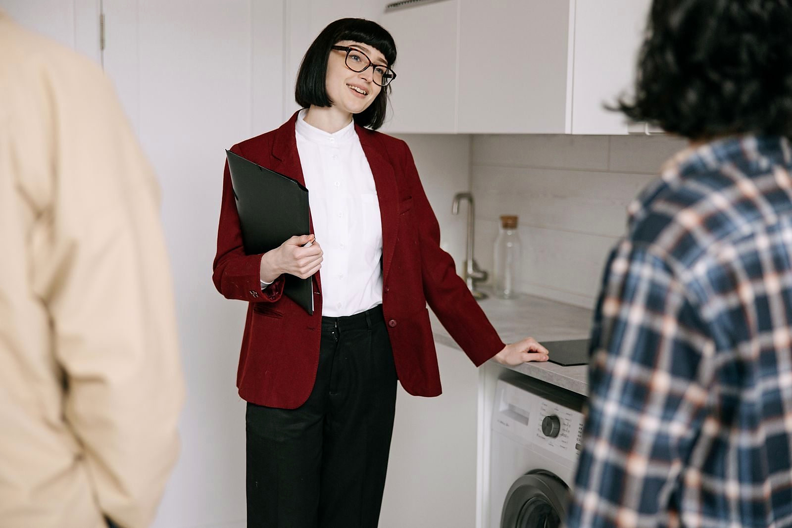 Real estate agent with clients in a modern kitchen during apartment viewing. Professional and engaging